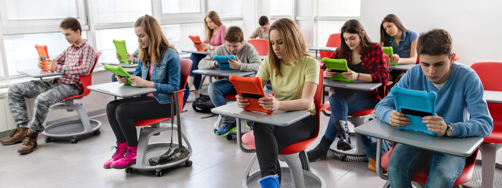 students reading at their desks, using tablets
